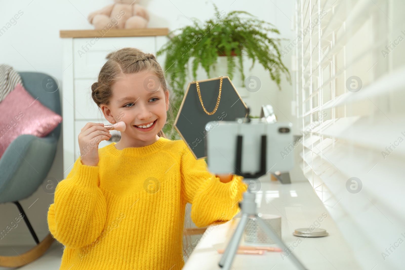 Photo of Cute little blogger with cosmetics recording video at home