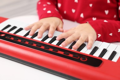 Photo of Little girl playing toy piano at home, closeup