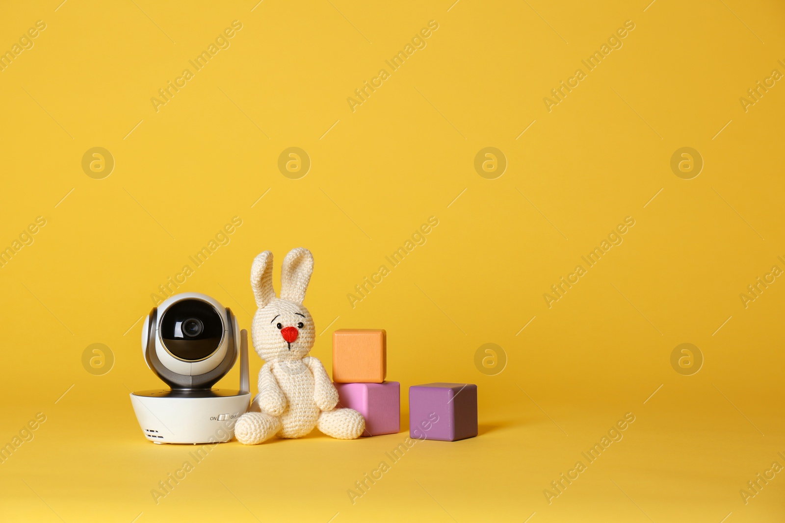 Photo of Modern CCTV security camera, toy bunny and cubes on color background. Space for text
