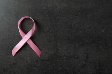 Photo of Pink ribbon and space for text on dark background, top view. Breast cancer awareness concept
