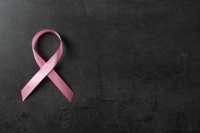 Pink ribbon and space for text on dark background, top view. Breast cancer awareness concept