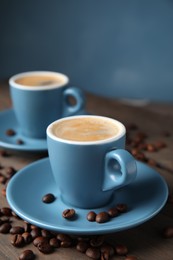 Photo of Cups of tasty espresso and scattered coffee beans on wooden table