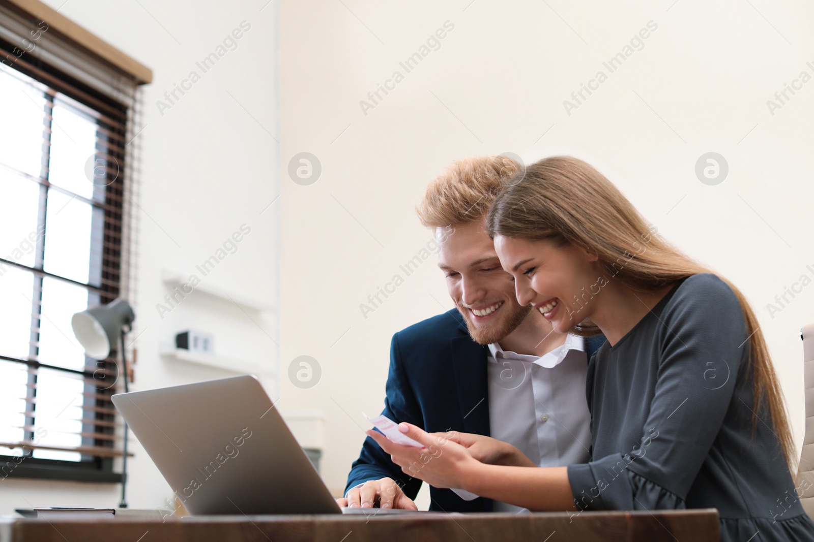 Photo of Happy young people with ticket checking results using laptop in office