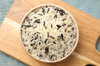 Photo of Mix of brown and polished rice on wooden table, flat lay