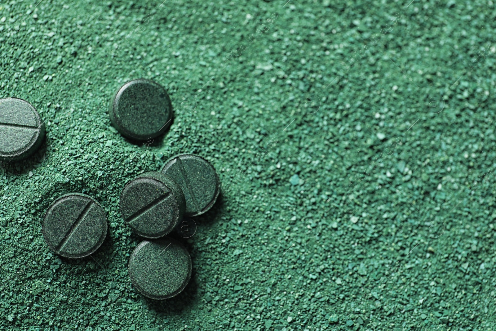 Photo of Natural green spirulina powder and pills as background, closeup. Space for text