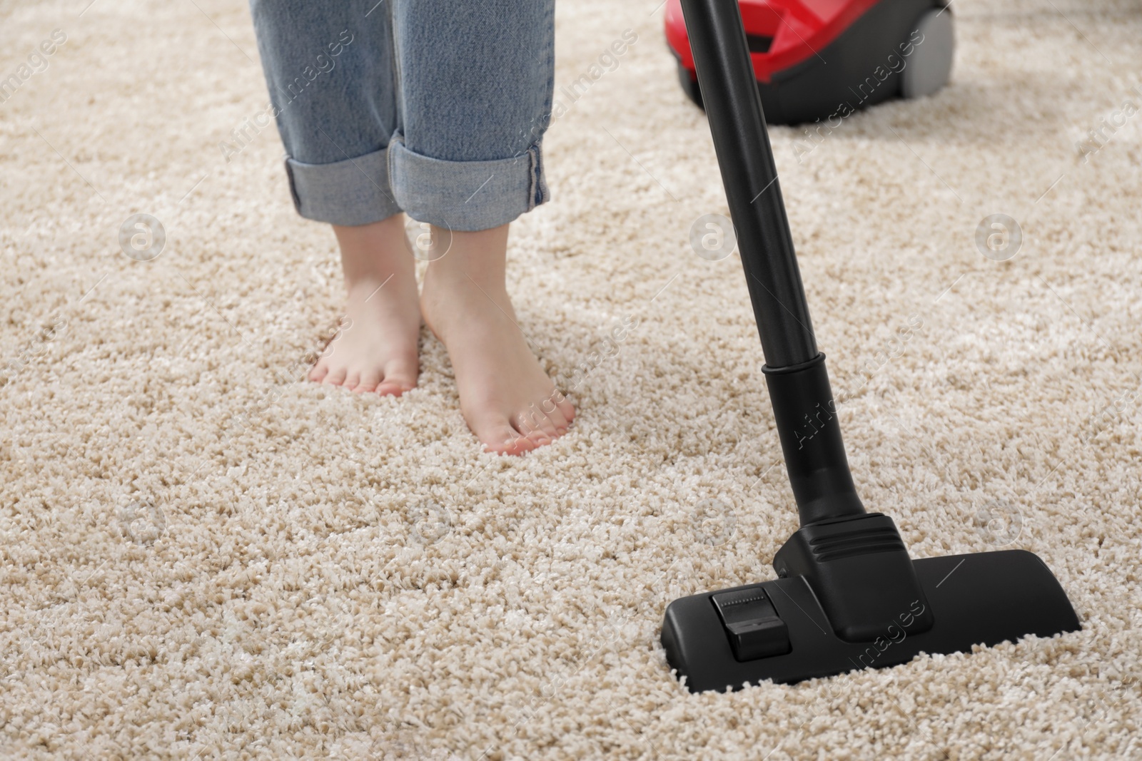 Photo of Woman cleaning carpet with vacuum cleaner at home, closeup