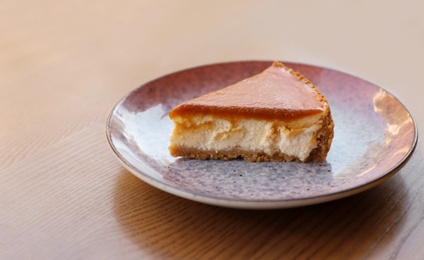 Plate with slice of cake on wooden table