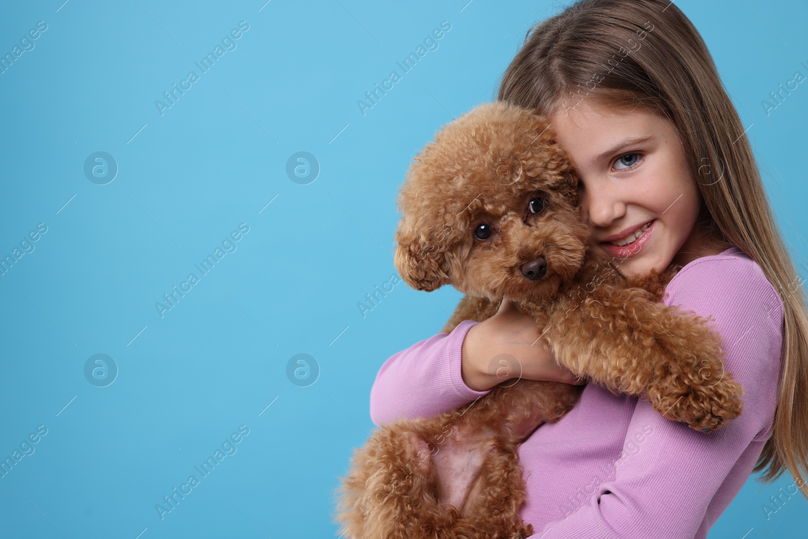 Photo of Little child with cute puppy on light blue background, space for text. Lovely pet