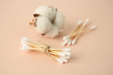 Photo of Cotton buds and flower on beige background, closeup