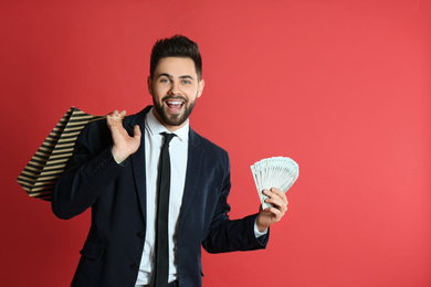 Photo of Young man with money and shopping bag on crimson background