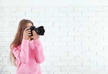 Female photographer with camera on brick background