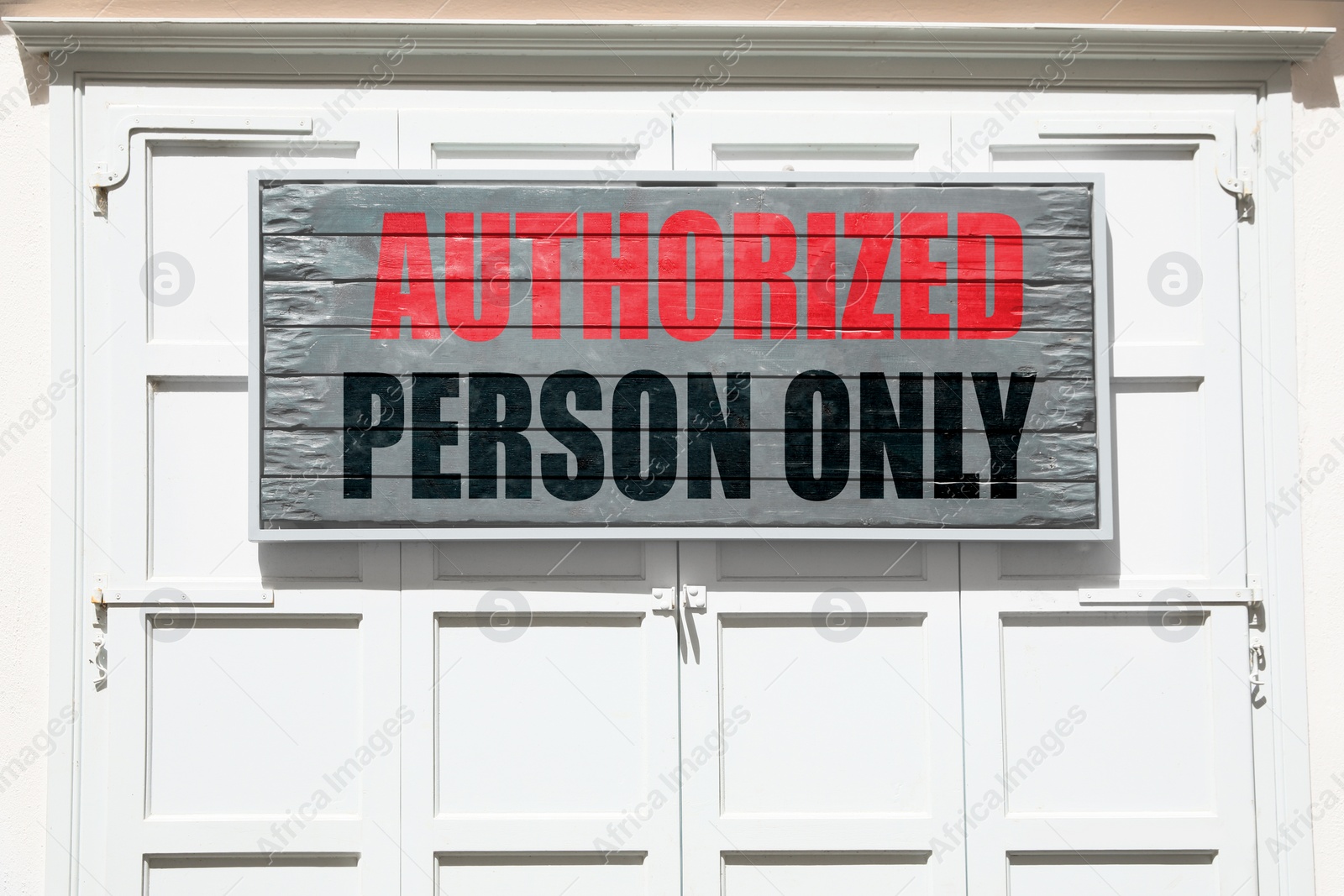 Image of Board with text Authorized Person Only on white shutters garage door outdoors