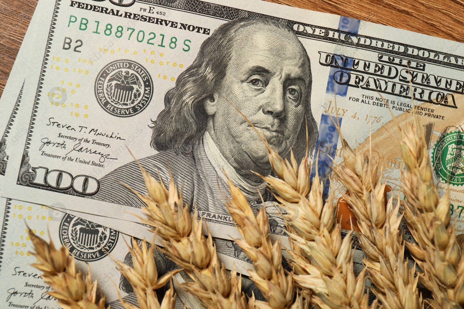 Photo of Dollar banknotes and wheat ears on wooden table, top view. Agricultural business