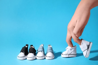 Photo of Woman with walking fingers wearing toy canvas shoes on light blue background, closeup