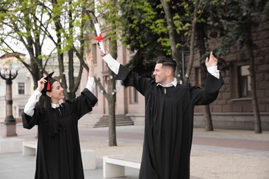 Photo of Happy students with diplomas after graduation ceremony outdoors