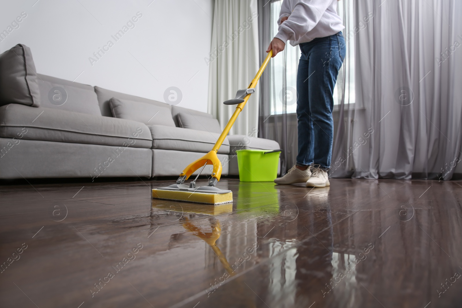 Photo of Woman cleaning parquet floor with mop indoors, closeup