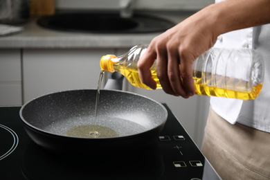 Photo of Man pouring cooking oil from bottle into frying pan, closeup