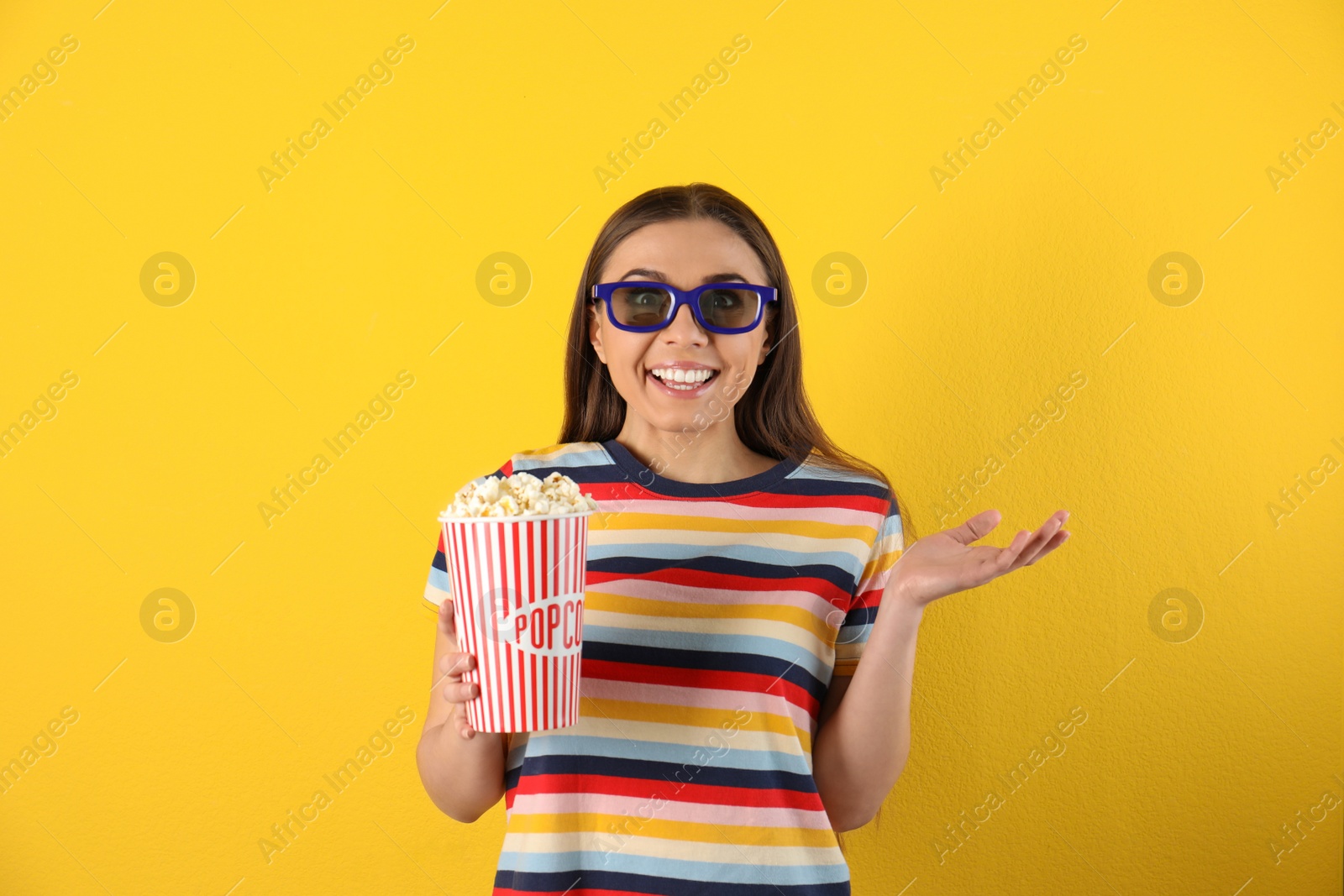 Photo of Emotional woman with 3D glasses and tasty popcorn on color background