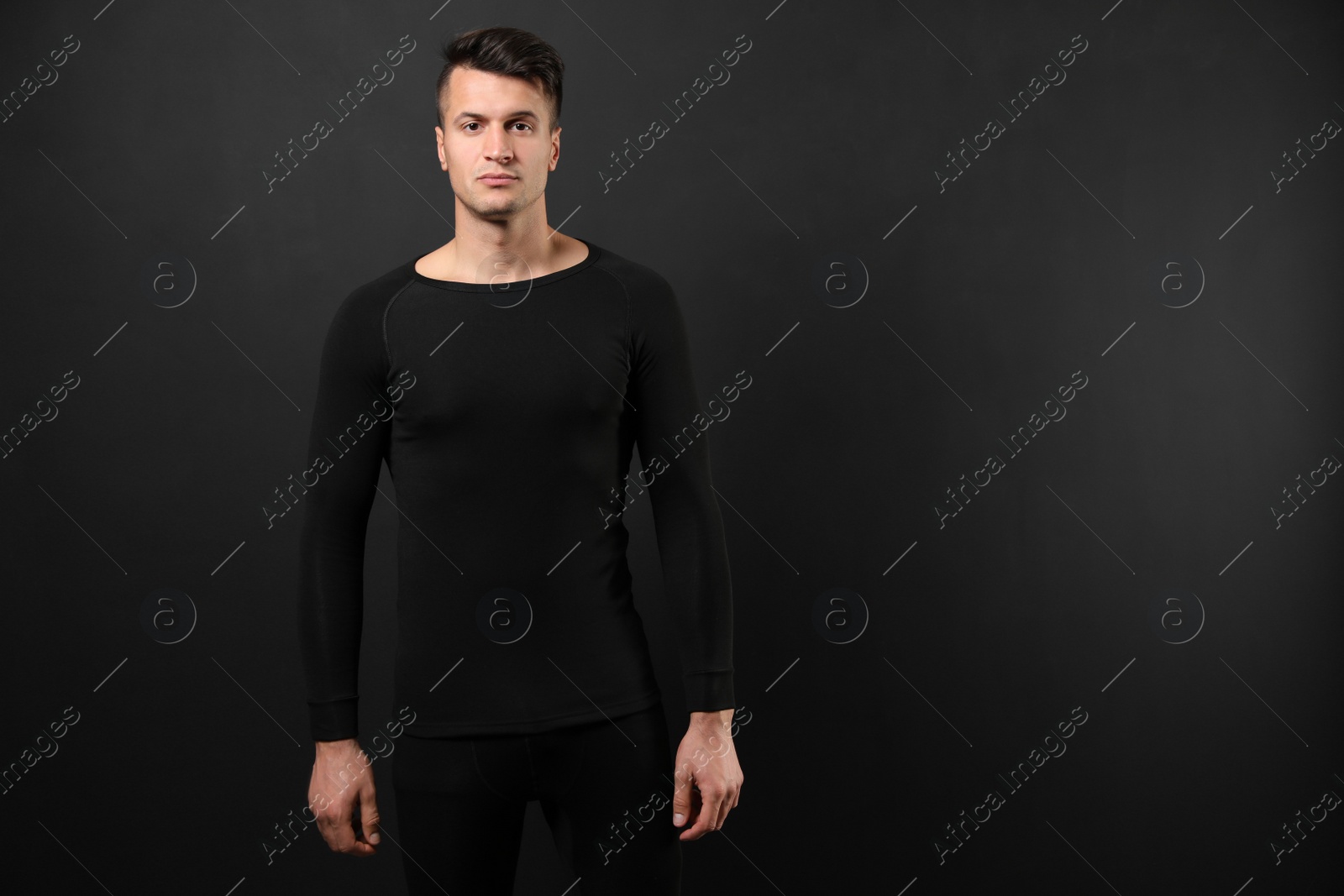 Photo of Man wearing thermal underwear on black background. Space for text