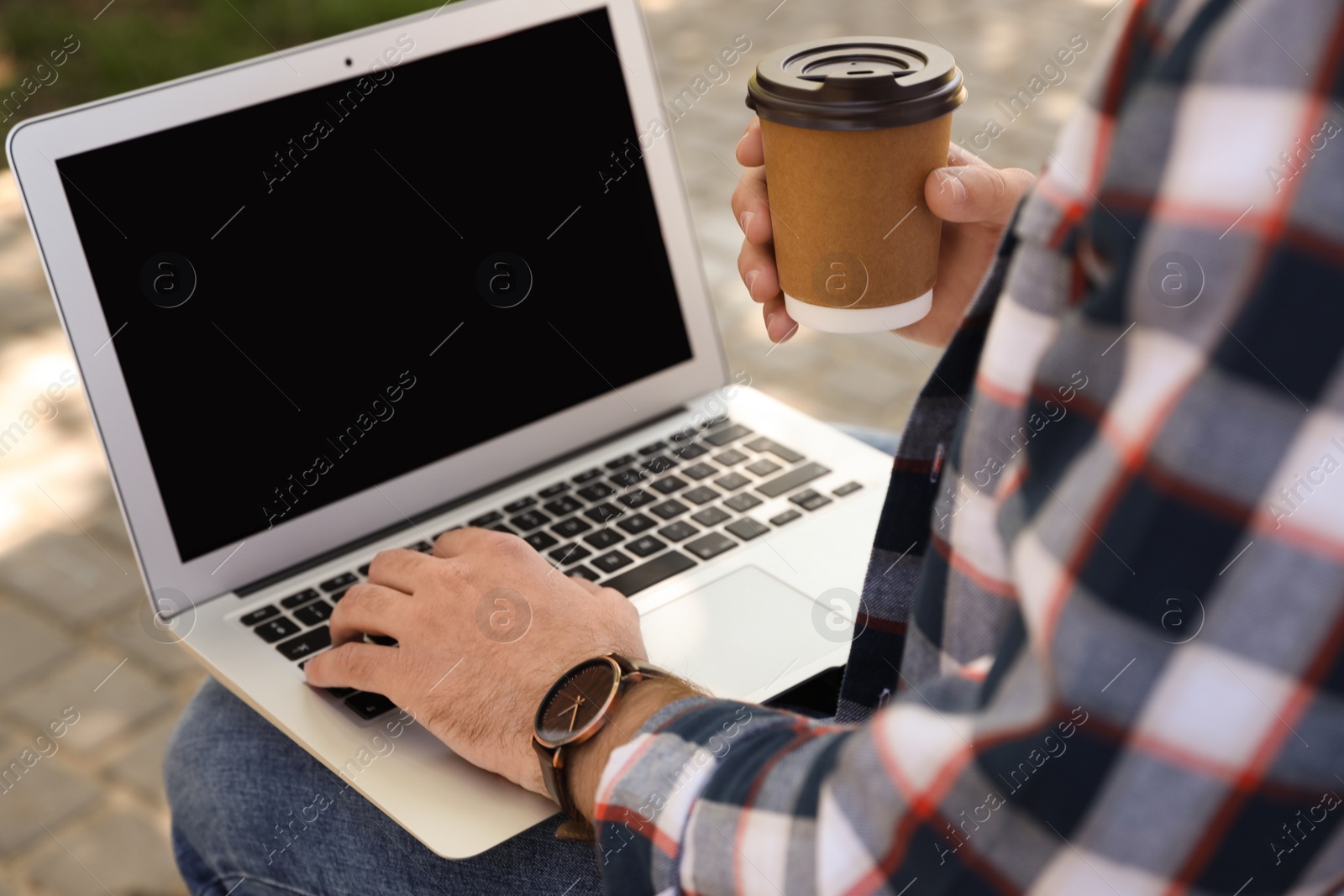 Photo of Young man using laptop outdoors, closeup. Space for text