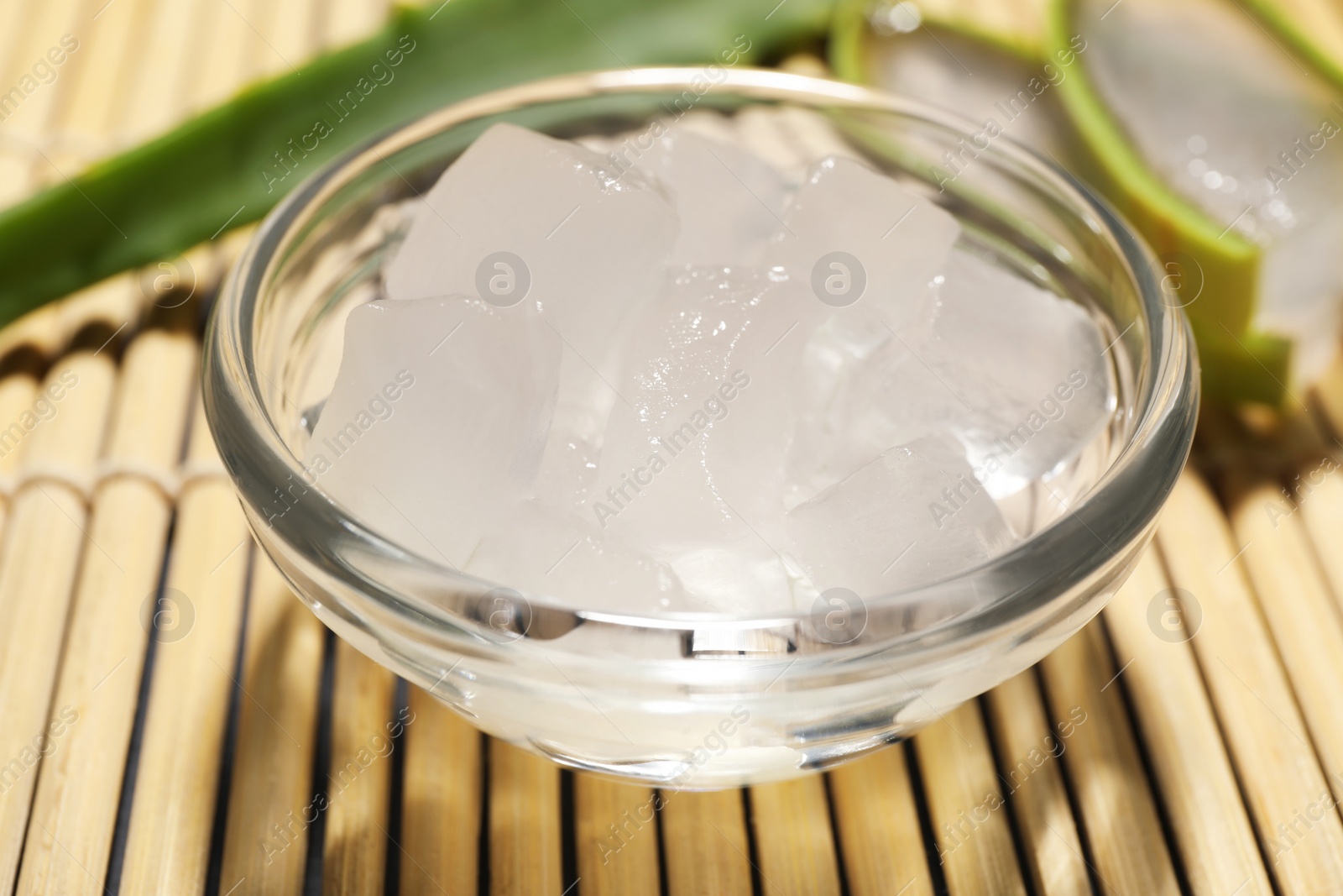 Photo of Aloe vera gel and slices of plant on bamboo mat, closeup