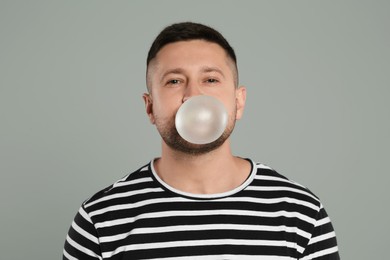 Photo of Handsome man blowing bubble gum on light grey background