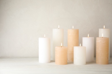 Burning candles on table against light background. Space for text