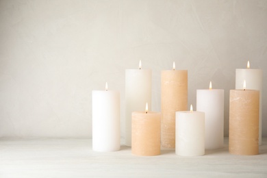 Photo of Burning candles on table against light background. Space for text