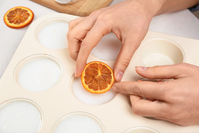 Photo of Woman making natural handmade soap at white table, closeup