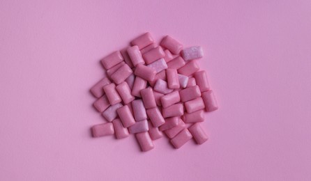 Photo of Heap of tasty sweet chewing gums on pink background, flat lay