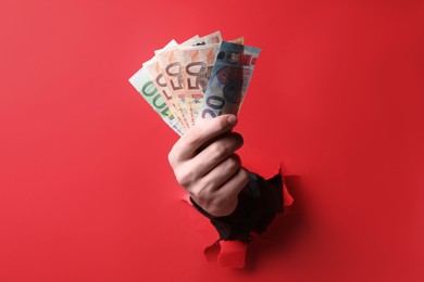 Photo of Businessman breaking through red paper with money in hand, closeup