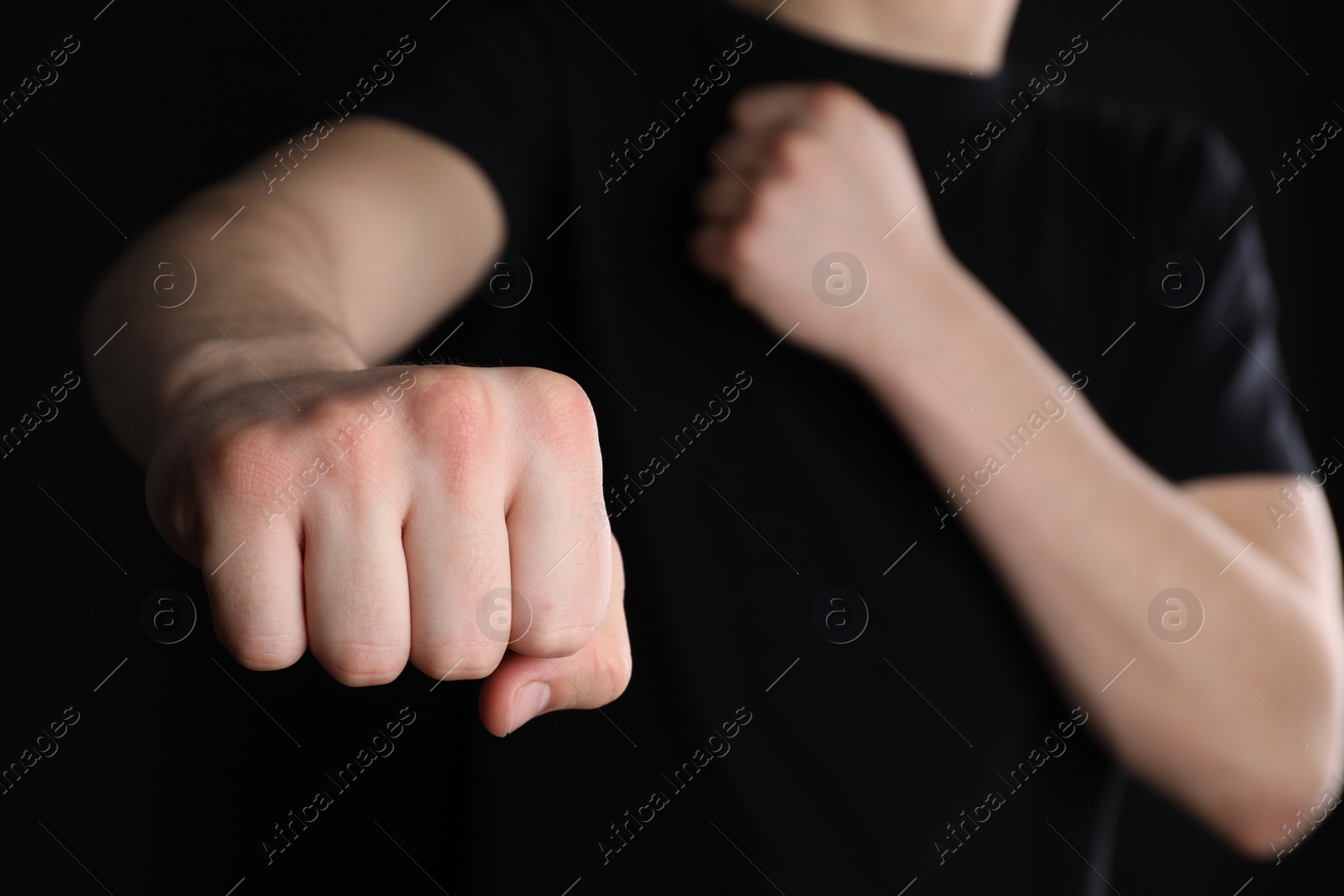 Photo of Man showing fist with space for tattoo on black background, selective focus