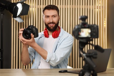 Smiling technology blogger with camera recording video review at home