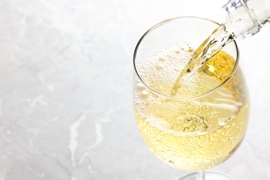 Photo of Pouring tasty aromatic wine in glass at gray marble table, closeup. Space for text