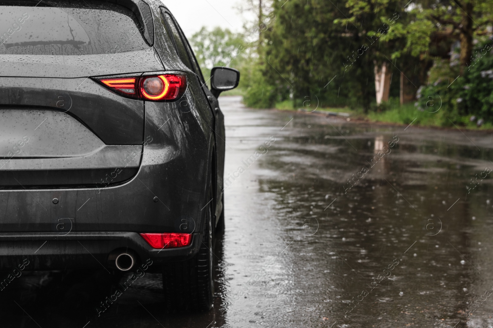 Photo of Modern car parked outdoors on rainy day