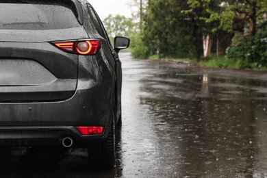 Photo of Modern car parked outdoors on rainy day