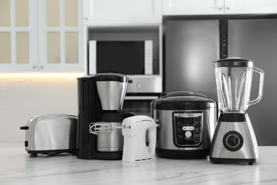 Photo of Set of modern home appliances on white marble table in kitchen