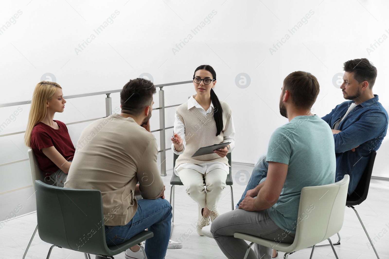 Photo of Psychotherapist working with group of drug addicted people at therapy session indoors