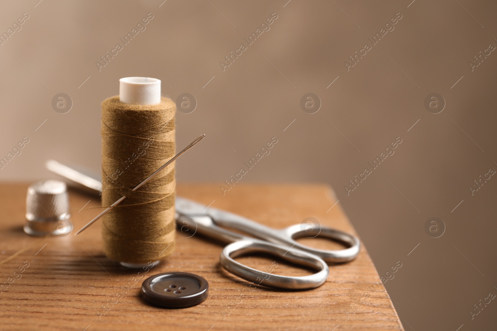 Photo of Scissors and other sewing accessories on wooden table, space for text