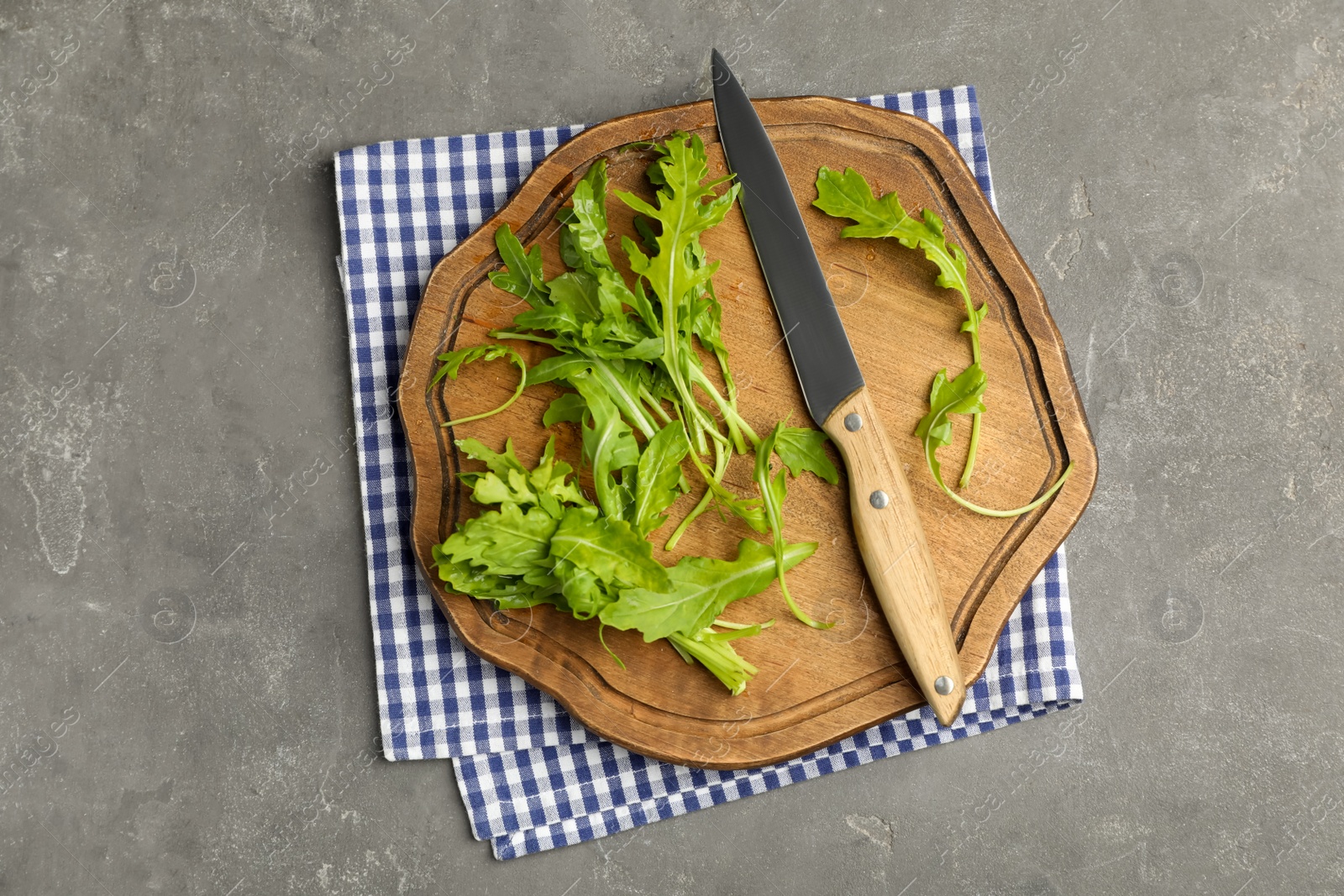 Photo of Fresh arugula, cutting board and knife on grey table, flat lay