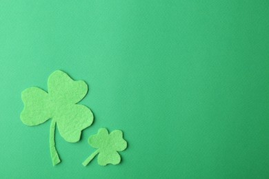 St. Patrick's day. Decorative clover leaves on green background, flat lay. Space for text