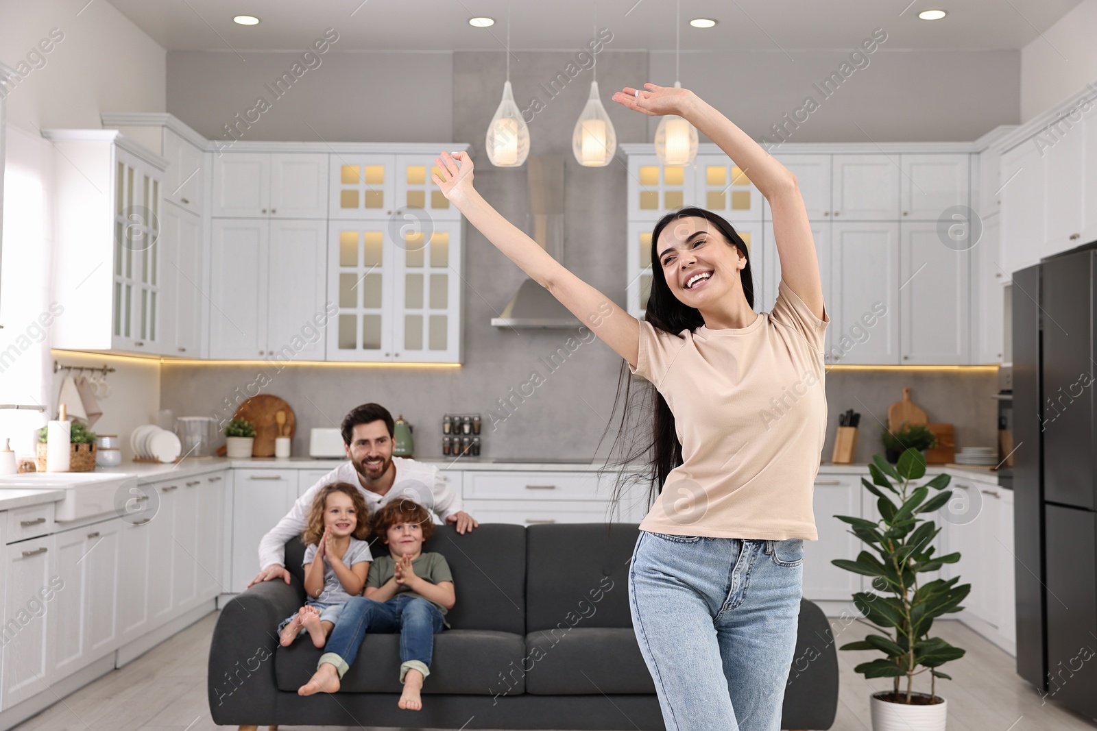 Photo of Happy family having fun at home. Mother dancing while her relatives resting on sofa