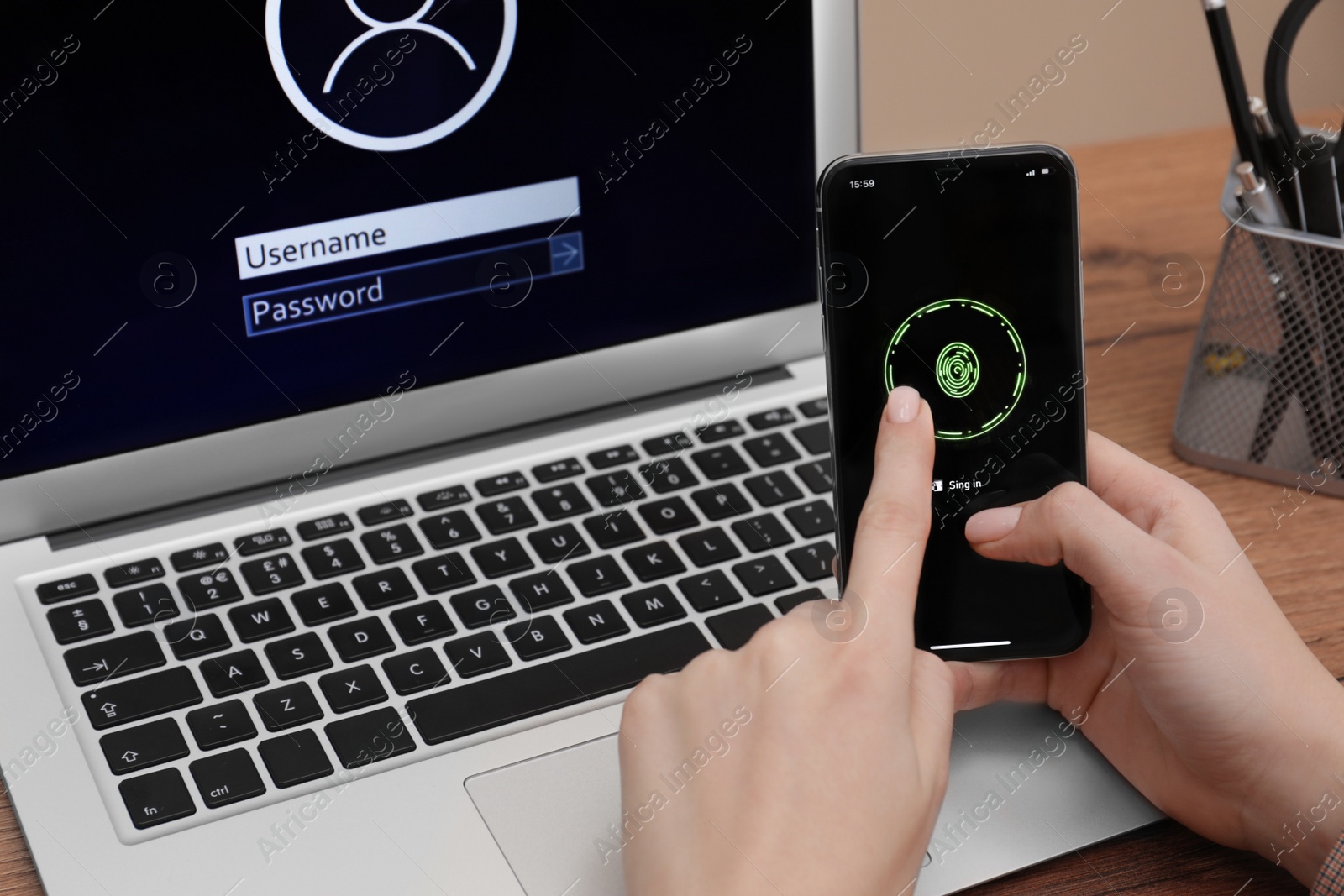 Photo of Woman unlocking smartphone with fingerprint identification near laptop at workplace , closeup. Reliable password