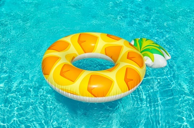 Bright inflatable pineapple ring floating in swimming pool on sunny day