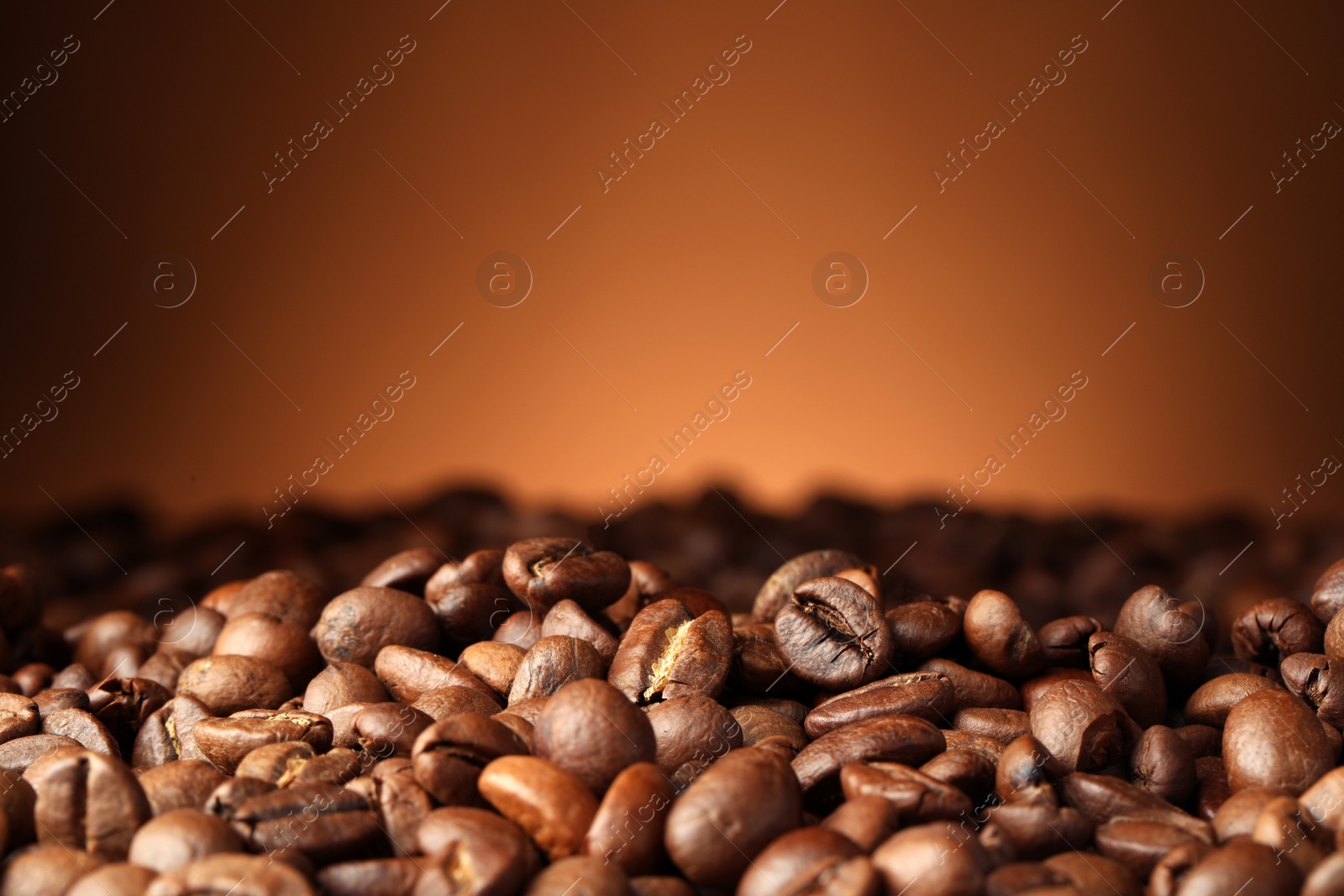 Photo of Heap of aromatic roasted coffee beans on brown background, closeup