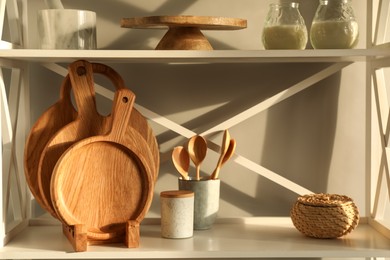 Photo of Wooden cutting boards, kitchen utensils and decor on shelving unit