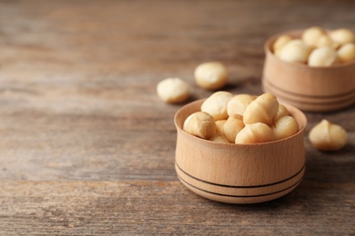 Photo of Bowl with shelled organic Macadamia nuts and space for text on wooden background
