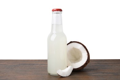 Delicious kombucha in glass bottle and coconut on wooden table against white background