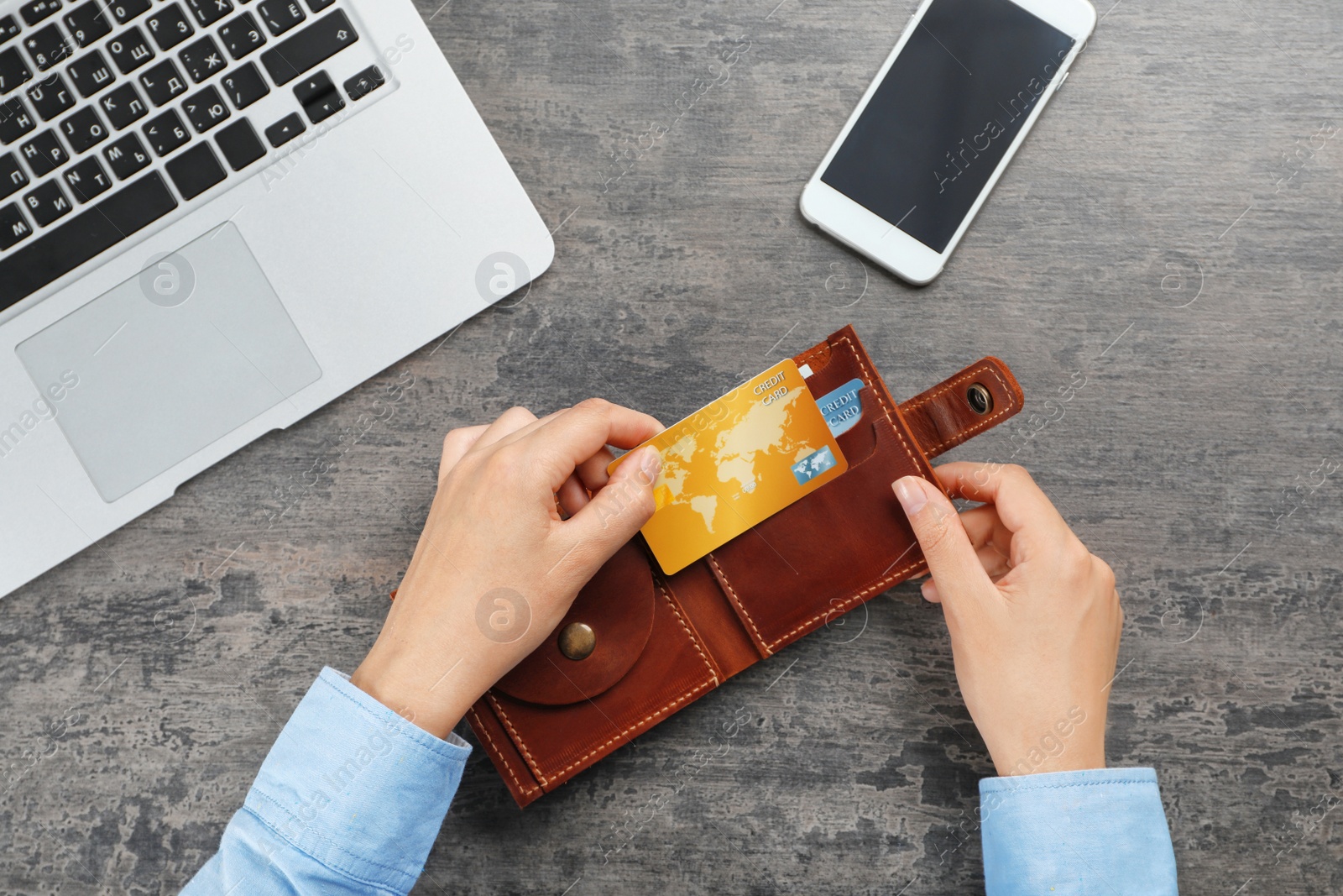 Photo of Woman holding leather wallet with credit cards on table, top view