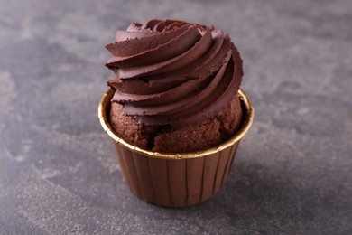 Delicious chocolate cupcake on grey textured table, closeup